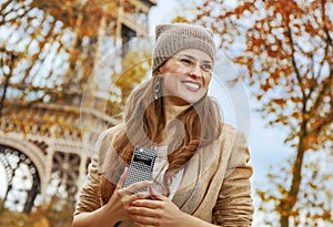 Tourist woman near Eiffel tower with cellphone looking aside