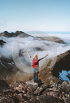 Tourist woman raised hands on mountain top over clouds travel activity summer vacations hike with backpack