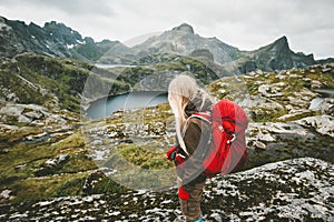 Tourist woman with red backpack hiking in mountains