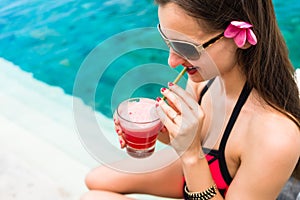 Tourist woman in red bikini drinking cocktail at beach