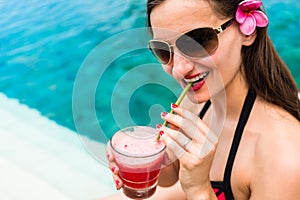 Tourist woman in red bikini drinking cocktail at beach