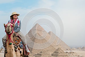 tourist woman riding a dromedary in front of pyramids. Egypt, Cairo - Giza