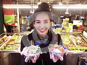 Tourist woman showing salmon sashimi most popular delicious food in street food tsukiji fish market, Japan