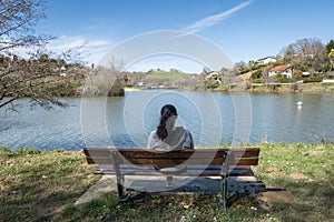 Tourist woman sitting facing the lake enjoying the scenery
