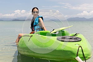 Tourist woman sitting on kayak lookign at beautiful tropical beach on vacation.