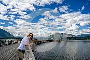 Tourist woman smiling into the camera on Salmon Arm Wharf, the longest freshwater wooden wharf in North America