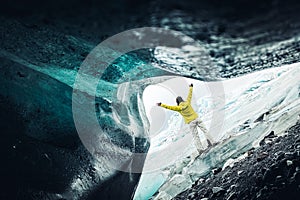 Tourist woman stand by beautiful Fjallsjakull glacier in Iceland in overcast day. Ice caves in Iceland. View from small gap cave