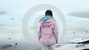 Tourist woman stand by beautiful Fjallsjokull glacier on ice in Iceland. Inspirational travel explore holidays Iceland concept