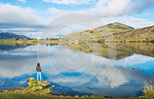 Tourist woman standing and looking to spectacular view of lake Hayes, New Zealand.