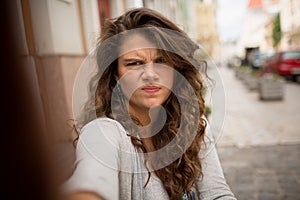 Tourist woman in the street on selfie shot showing gloomy face.