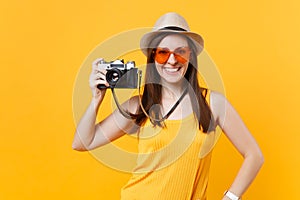 Tourist woman in summer casual clothes, hat take picture on retro vintage photo camera isolated on yellow background