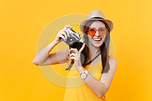 Tourist woman in summer casual clothes, hat take picture on retro vintage photo camera isolated on yellow background