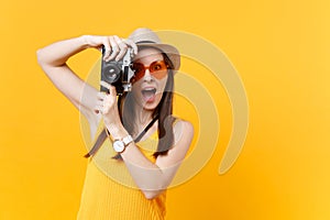 Tourist woman in summer casual clothes, hat take picture on retro vintage photo camera isolated on yellow background