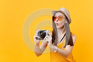 Tourist woman in summer casual clothes, hat take picture on retro vintage photo camera isolated on yellow background