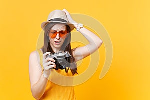 Tourist woman in summer casual clothes, hat take picture on retro vintage photo camera isolated on yellow background