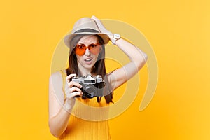 Tourist woman in summer casual clothes, hat take picture on retro vintage photo camera isolated on yellow background