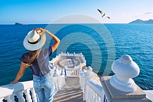 Tourist woman in sun hat enjoying sea view at Balcon del Mediterraneo in Benidorm, Spain. Summer vacation in Spain