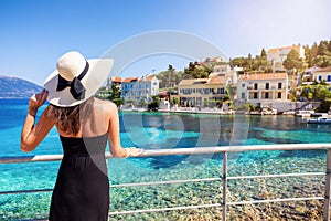 A tourist woman with sunhat looks at the beautiful village of Fiscardo, Kefalonia, Greece