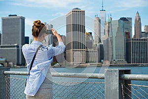 Tourist woman taking travel picture with camera of Manhattan Skyline and New York City skyline during autumn holidays.