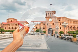 Tourist woman with toy airplane on the background of a Republic Square in Yerevan. Concept of air flight transportation in