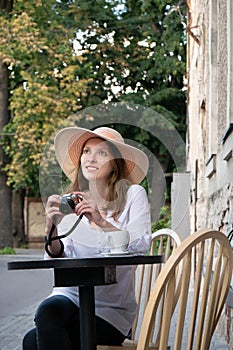 Tourist woman digital camera street cafe terrace girl hat sun vintage travel photo shooting white cup coffee panasonic lumix