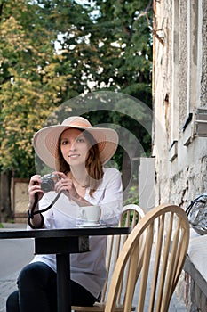 Tourist woman digital camera street cafe terrace girl hat sun vintage travel photo shooting white cup coffee panasonic lumix