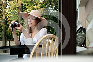 Tourist woman digital camera street cafe terrace girl hat sun vintage travel photo shooting white cup coffee panasonic lumix