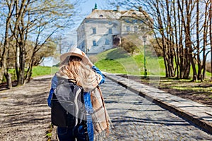 Tourist woman visiting Olesko Castle walking along alley to ancient landmark. Travelling in Western Ukraine.