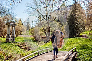 Tourist woman visiting Olesko Castle walking in spring park by ancient arch. Travelling in Western Ukraine
