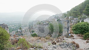 Tourist woman walking along ruined buildings in old mountain town. Traveling woman going on trail in ancient city on