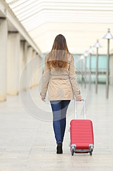 Tourist woman walking carrying a suit case in an airport