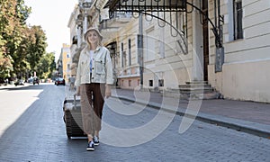 tourist woman walks with a suitcase down the street in a European city, tourism in Europe. Walking the streets. Copy