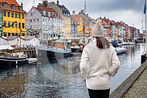 A tourist woman in winter clothing enjoys the view to the beautiful Nyhavn area