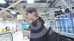 Tourist young girl teen with backpack with suitcase up down the escalator the airport lifestyle waiting for the plane