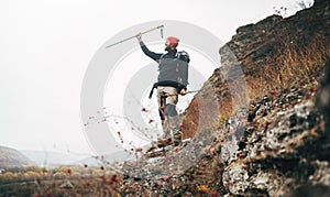 Tourist young male hiking in mountains, finished his track. Landscape view of traveler bearded man trekking and mountaineering