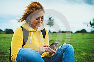 Tourist young smile girl on background green grass using mobile smartphone, women holding in female hands gadget technology, hiker