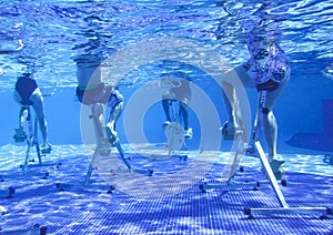 Touristen doing aqua aerobics on exercise bikes in swimming pool tropical hotel