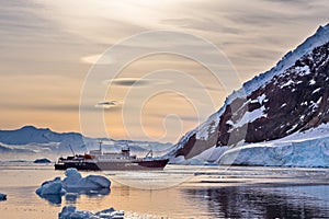 Touristic antarctic cruise vessel among the icebergs with glacie