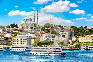 Touristic sightseeing ships in Golden Horn bay of Istanbul and view on Suleymaniye mosque with Sultanahmet district against blue