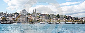 Touristic sightseeing ships in Golden Horn bay of Istanbul and view on Suleymaniye mosque with Sultanahmet district against blue