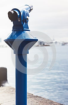 Touristic telescope look at the city and sea with sunset view of Barcelona Spain, close up old blue binoculars on background view