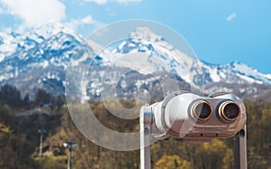 Touristic telescope look at the city with view snow mountains, closeup binocular on background viewpoint observe vision, metal