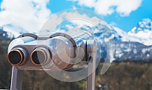 Touristic telescope look at the city with view snow mountains, metal binocular on background viewpoint observe vision, closeup