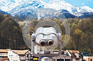 Touristic telescope look at the city with view snow mountains, metal binocular on background viewpoint observe vision, closeup