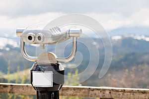 Touristic telescope look on top of mountains, close up metal binoculars on background viewpoint overlooking mountain