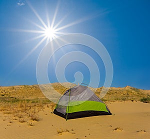 Touristic tent among sandy desert under a sparkle sun