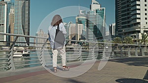 touristic trip in UAE, woman walking alone in Dubai Marina in daytime, admiring creek and buildings