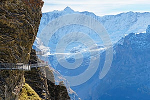 Tourists admire majestic snowy alpine mountains along a hair-raising cliffwalk