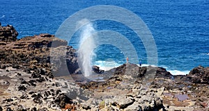 Tourists admiring the Nakalele blowhole on the Maui coastline. A jet of water and air is violently forced out through the hole in