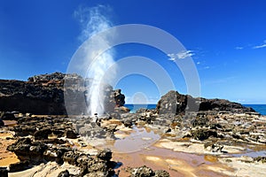 Tourists admiring the Nakalele blowhole on the Maui coastline. A jet of water and air is violently forced out through the hole in